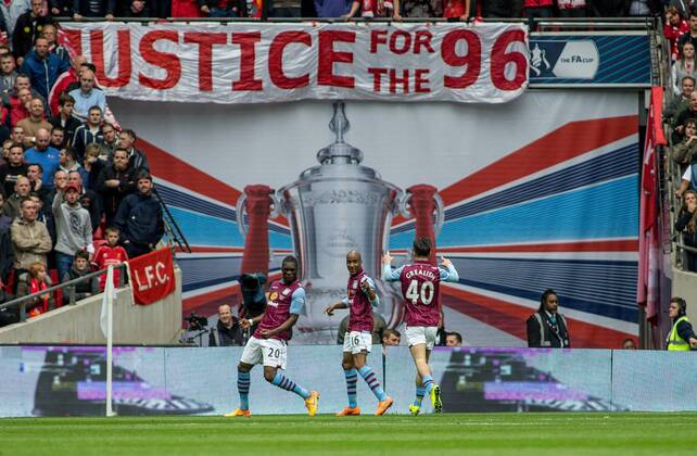 Christian Benteke of Aston Villa celebrates his goal with Fabian Delph and Jack Grealish of Aston Villa in front of the Liverpool fans and the Justice for the 96 banner during the The FA Cup Semi-Final match between Aston Villa and Liverpool at Wembley Stadium, London, England on 19 April 2015. Copyright: xLiamxMcAvoyx 03950092