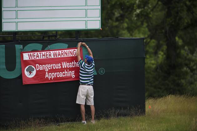 170614 En funktionär sätter upp en skylt som varnar för ett oväder som drar in över golfbanan Erin Hills inför golfturneringen US Open den 14 juni 2017 i Hartford.  Copyright: JOELxMARKLUND BB170614JM031