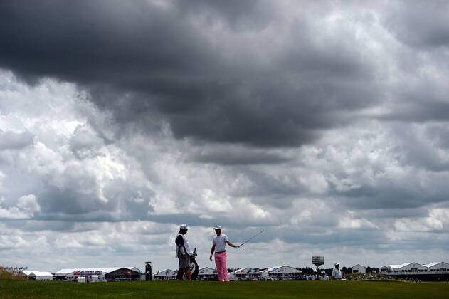 Justin Thomas (R) talks with his caddie as he waits for the group ahead on the 10th fairway during round 3 of the 117th U.S. Open golf tournament at Erin Hill golf course on June 17, 2017 in Erin, Wisconsin.  WIS20170617110 BRIANxKERSEY