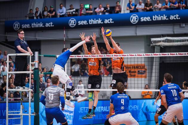 Friedrichshafen Germany 26 04 2018 Athanasios Protopsaltis Friedrichshafen 7 against the block from Paul Carroll BR Volleys 12 and Graham Vigrass BR Volleys 8 in the Playoff Final Game 1 of the Volleyball Bundesliga between VfB Friedrichshafen and the Berlin Recycling Volleys