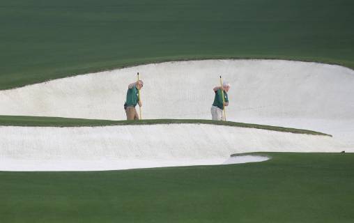 Workers rake a sand trap on the Monday before the 2019 Masters Tournament at Augusta National Golf Club in Augusta, Georgia, on April 8, 2019.  AUG20190408101 JOHNxANGELILLO