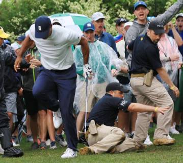 Golf: Masters Tournament Tiger Woods is almost felled by a sliding security guard after hitting his second shot on the 14th hole during the second round of the Masters Tournament at Augusta National Golf Club in Augusta, Georgia, on April 12, 2019. 