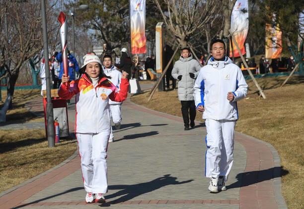 (220204) -- BEIJING, Feb. 4, 2022 -- Torch bearer Wang Caihong (L) runs with the torch during the Beijing 2022 Olympic Torch Relay at the Grand Canal Forest Park in Tongzhou District of Beijing, capital of China, Feb. 4, 2022. ) (BEIJING2022)CHINA-BEIJING-OLYMPIC TORCH RELAY (CN) RenxChao 