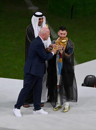 FOOTBALL World Cup 2022 Final Argentina France 18 12 2022 Lionel Messi in cape Bischt receives the World Cup trophy from Tamim bin Hamad Al Thani Emir of Qatar and Fifa President Gianni Infantino