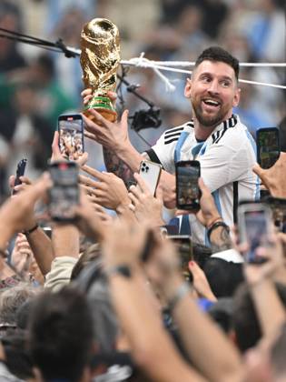 Football, men, season 2022 23, World Cup in Qatar, final, Argentina France 2 2, 3 3 n V, 4 2 i E at Lusail Iconic Stadium in Lusail, Lionel Messi Argentina with trophy, he is carried on shoulders long after the end of the game in the area behind the goal, he is photographed and filmed by fans with cell phones, cheering after the final whistle, 18 12 2022, Copyright: xMatthiasxKochx