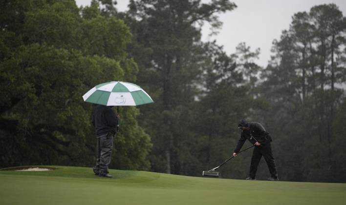 Grounds crew squeegee the 18th green at the conclusion of the rain delayed second round at the 87th Masters tournament at Augusta National Golf Club in Augusta, Georgia on Saturday, April 8, 2023. Brooks Kopek leads the tournament at 132, 12 under par.  AUG20230408206 BOBxSTRONG