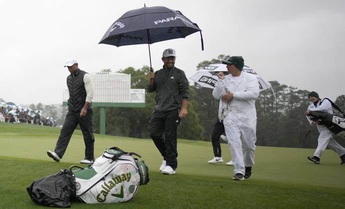 Tiger Woods (L) and Xander Schauffele (C) leave the 18th green after completing the rain delayed second round at the 87th Masters tournament at Augusta National Golf Club in Augusta, Georgia on Saturday, April 8, 2023. Woods made the cut finishing at 147. Schauffele finished at 142.  AUG20230408223 BOBxSTRONG