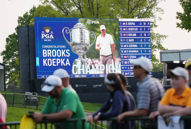 Fans walk past a leaderboard after Brooks Koepka won the 2023 PGA, Golf Herren Championship at Oak Hill Country Club in Rochester, New York on Sunday, May 21, 2023. Koepka won the championship shooting 72, 66, 66 and 67 to finish at nine-under-par.  ROC20230521596 AARONxJOSEFCZYK