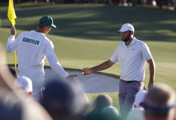 Scottie Scheffler is congratulated by his caddie Ted Scott after sinking a birdie putt on the eighteenth hole during the third round of the Masters Tournament at Augusta National Golf Club in Augusta, Georgia on Saturday, April 13, 2024. Scheffler ended the day in the lead at seven-under-par.  AUG20240413559 TANNENxMAURY