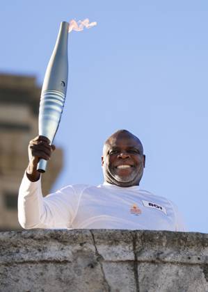 Paris Olympic torch relay begins Former French football player Basile Boli raises the Olympic torch in Marseille on May 9, 2024, as the Paris Olympic torch relay begins following the arrival of the Olympic flame in the southern French port city on a majestic three-mast ship. About 10,000 torchbearers are to pass through over 400 towns until the games opening ceremony in Paris on July 26.  A14AA0002809050P
