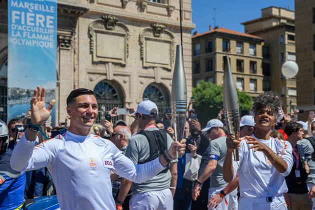 (240509) -- MARSEILLE, May 9, 2024 -- Dancer Maryam Kaba (R) passes the Olympic Torch to local firefighter Matthieu Gudet during the relay of the Olympic flame of Paris 2024 in Marseille, France, May 9, 2024. (Photo by Xinhua) (SP)FRANCE-MARSEILLE-2024 PARIS OLYMPIC-TOURCH RELAY JulienxMattia 