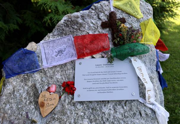 Here in the picture the memorial, temporary memorial for the former biathlete, Laura Dahlmeier from Garmisch Partenkirchen, who died in a mountaineering accident on Laila Peak, Karakorum Mountains in Pakistan, in the small spa park with a picture photo, numerous flowers and candles and a stone that looks like a mountain and is provided with Tibetan prayer flags and a saying sign, say goodbye.