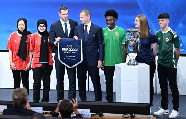 Ireland and United Kingdom confirmed to co-host 2028 UEFA European Football Championship GENEVA, SWITZERLAND - OCTOBER 10: UEFA President Aleksander Ceferin (C) and Welsh retired professional footballer, heading the delegation of UK and Ireland Gareth Bale (3rd L) hold the pennant as they pose with the pennant next to the trophy after United Kingdom and Ireland were elected to host the Euro 2028 football tournament during a ceremony held after the Executive Board meeting at the UEFA headquarters in Nyon, Geneva, Switzerland on October 10, 2023. Geneve Isviçre. Editorial use only. Please get in touch for any other usage. Copyright: x2025xAnadoluxDursunxAydemirx