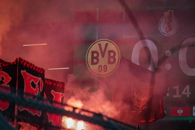 Germany Football DFB Cup 2025 26, Round of 16 Borussia Dortmund vs Bayer 04 Leverkusen Signal Iduna Park Dortmund Pyro in the curve, red glowing smoke in front of BVB logo and DFB Cup scoreboard, fan curve dynamics, Ultras, fan culture, derby heat, emotions, safety debate, stadium safety, fan protests, Bundesliga, national cup round, identity, tradition, atmosphere, stadium politics, media focus, major event, spectator atmosphere Copyright: xJOERANxSTEINSIEKx