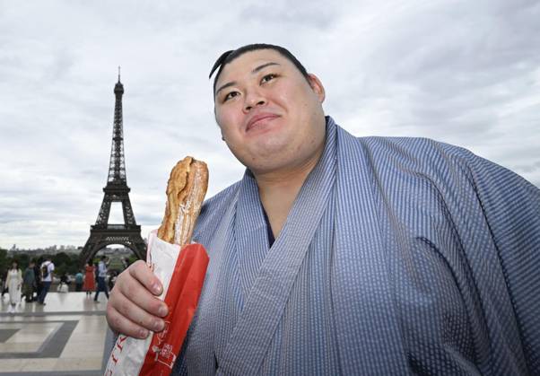 Sumo: Paris tournament Sumo grand champion Onosato is pictured with a baguette while sightseeing around Paris landmark Eiffel Tower on June 11, 2026, ahead of a June 13-14 sumo tournament in the French capital.  A14AA0005618477P