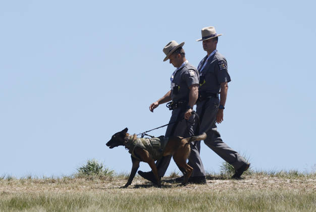 State Troopers walk with a police dog while players have a practice round on the Monday before the 126th U.S. Open Golf Championship at Shinnecock Hills Golf Club on Monday, June 15, 2026 in Southampton, New York.  NYP20260615318 JOHNxANGELILLO