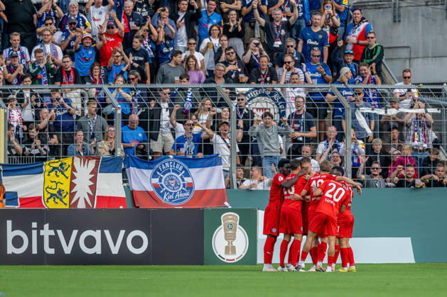 Kiel fans cheer in front of their own fan section as Phil Harre of Holstein Kiel, 19, scores the 0-1 goal (GER), TSV 1860 Munich vs. Holstein Kiel, Soccer, DFB Cup, 1st Round, 2026-2027 Season, August 22, 2026 DFL DFB regulations prohibit any use of photographs as image sequences and or quasi-video. Photo: HMB Media, Heike Feiner Copyright: HMBxMedia HeikexFeiner