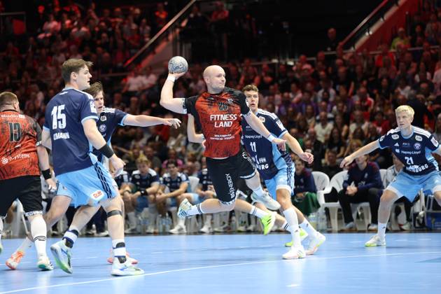 Melf Hagen 20 of MTV Braunschweig rises for a jump shot at the Volkswagen Halle in Braunschweig, surrounded by Dominik Axmann 15 of HSV Hamburg, Nicolaj Jørgensen 11 of HSV Hamburg, and Frederik Bo Andersen 21 of HSV Hamburg. The Hamburg defense tries to block the shot, while the crowd watches the action up close. Melf Hagen 20 of MTV Braunschweig attempts a jump shot against HSV Hamburg. Copyright: xspeedshotx