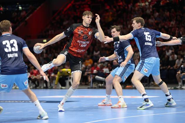 Rick Harder of MTV Braunschweig breaks through the HSV Hamburg defense while jumping with the ball, including Dominik Axmann (15) and Moritz Sauter (33). The scene shows a dynamic offensive drive in the packed Volkswagen Halle in Braunschweig. Rick Harder (40) of MTV Braunschweig breaks through against HSV Hamburg. Copyright: xspeedshotx