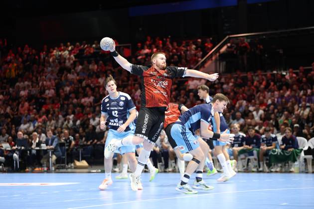 Niklas Wolters of MTV Braunschweig takes a shot while several HSV Hamburg players defend. The Volkswagen Halle in Braunschweig is packed with spectators. Niklas Wolters of MTV Braunschweig takes a shot against HSV Hamburg. Copyright: xspeedshotx