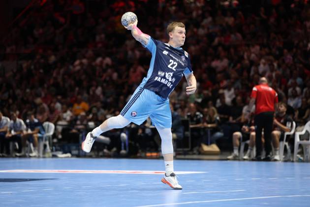 Noah Beyer, 22, of HSV Hamburg takes a shot at the Volkswagen Halle in Braunschweig and holds the ball aloft with his arm outstretched. The left wing can be seen in the middle of his shot, with one leg raised, with a well-filled spectator stand in the background. Noah Beyer, 22, of HSV Hamburg, taking a shot at the Volkswagen Halle Copyright: xspeedshotx