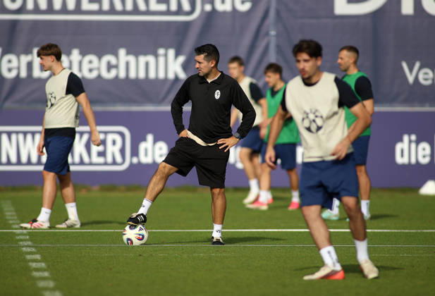 Soccer, Men s, Bavarian Regional League, 2026–2027 Season, TSV 1860 Munich, Practice, Grünwalder Strasse 114 Alper Kayabunar, coach of TSV 1860 Munich, standing on the practice field with one foot on the ball, watches his players