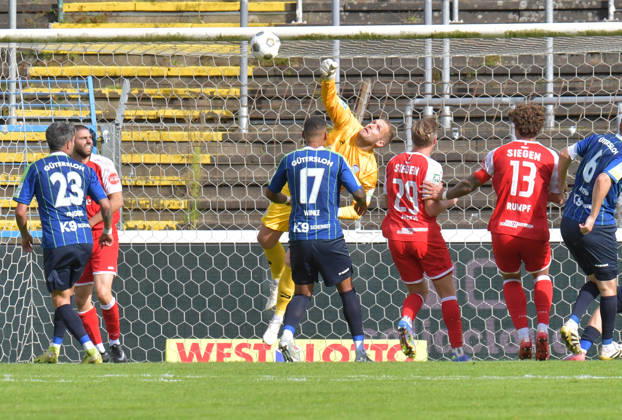October 10, 2026, GER, Soccer, Regionalliga West, 2026–2027 Season, Matchday 12, Ohlendorf Stadium in Heidewald, Gütersloh FC vs. Gütersloh SF Siegen 0–5: Jarno Peters (FC Gütersloh) blocks the ball; Serhat Semih Güler (SF Siegen) capitalizes on the rebound to make it 0–2—action, still image, wide shot, goalkeeper, save