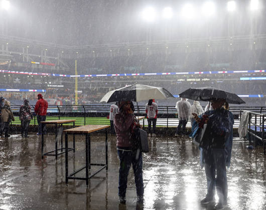 Baseball fans watch as a heavy rain falls before the start of game four of the MLB, Baseball Herren, USA American League Championship Series between the Tampa Bay Rays and the Cleveland Guardians at Progressive Field in Cleveland, Ohio, on Friday, October 16, 2026. The 8pm ET start of the game has been delayed due to the weather.  CLE20261016702 AARONxJOSEFCZYK