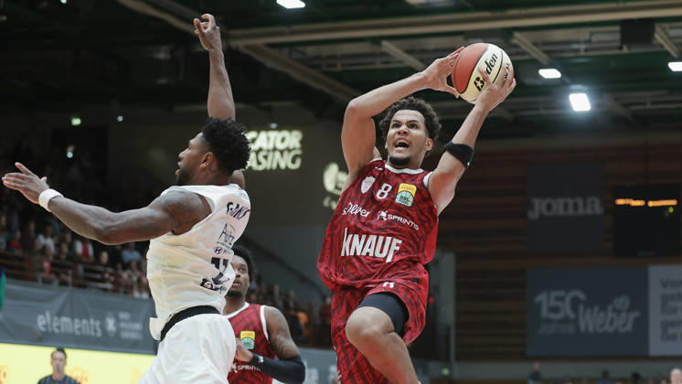 Pictured from left: Anthony Gaines of Syntainics MBC, No. 11, against Brandon Tischler of Wuerzburg Baskets, No. 8, on a layup, 18 10 2026, Fitness First Wuerzburg Baskets vs. SYNTAINICS MBC, Netto BBL Cup, Round of 16, Germany, 97072, tectake Arena Wuerzburg, Copyright: HMBxMedia xJulienxBecker