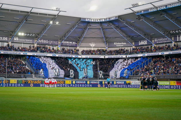 Germany Soccer Bundesliga 2026–2027, Matchday 7: SC Paderborn vs. Hamburger SV at Home Deluxe Arena in Paderborn. Wide shot of the Home Deluxe Arena in Paderborn; interior view featuring a large blue, black, and white choreographed display by SC Paderborn 07 home fans in the stands; HAMBURG fan choreography; Ultras, fan scene, spectators, flags, fan section, atmosphere, pre-game huddles for both teams, Hamburger SV, HSV, SC Paderborn, soccer, Bundesliga, sports venue, stadium roof, floodlights, playing field, sponsors, advertising, advertising banners, Merkur, buXtrade, Varnholt, Welcome Hotel Copyright: xJOERANxSTEINSIEKx