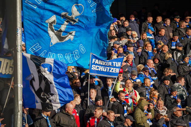 Germany Soccer Bundesliga 2026–2027, Matchday 7: SC Paderborn vs. Hamburger SV at Home Deluxe Arena in Paderborn. Away fans of Hamburger SV (HSV) in the visitors’ section at Home Deluxe Arena in Paderborn. Large blue-and-black HSV flags featuring an anchor and the word Hamburg, as well as a banner. Protecting fan culture: fans, ultras, the fan scene, fan culture, fan protest, spectators, flags, banners, stands, fan section, atmosphere, support, away game, soccer, Bundesliga, SC Paderborn 07, Hamburger SV, stadium, sports venue, fan rights, protect fan culture, wide shot Copyright: xJOERANxSTEINSIEKx