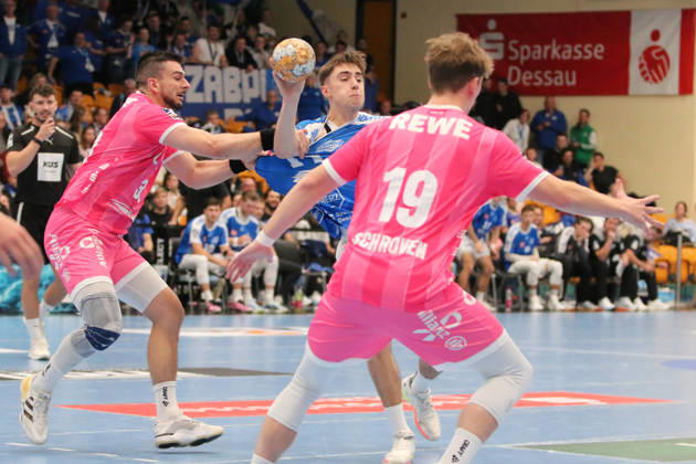 October 24, 2026 Men s Handball 2026–2027, 2nd Division, Matchday 9: Dessau Roßlauer HV 06 vs. SC DHfK Leipzig at Anhalt Arena, Dessau. Alen Hadzimuhamedovic, Dessau, 11, in blue, passes the ball while being held by Luka Rogan, Leipzig, 33, in pink; Dessau Roßlau, Saxony-Anhalt, Germany