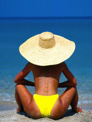 Junge Frau mit Sonnenhut schaut aufs Meer