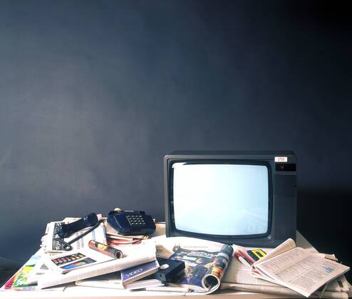 Arbeitsplatz mit Fernseher und Zeitungen