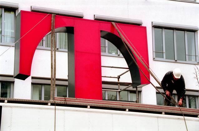 T-Logo der Deutschen Telekom wird auf dem Dach eines Firmengebäudes befestigt