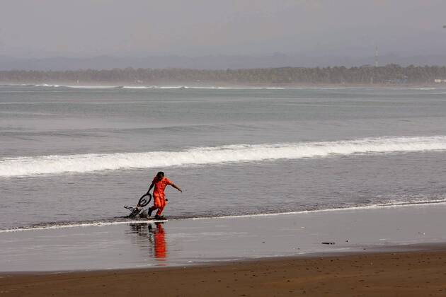 Rettungskraft zieht ein Fahrrad aus dem Meer nach dem Tsunami in Pangandaran auf Java - 