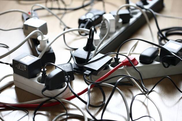 Mehrfachsteckdosenleiste, zum Anschluss von mehreren elektrischen Geräten. Wirrwarr von Kabeln, Steckern, Netzgeräten.