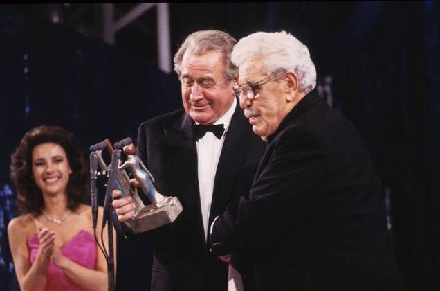 TeleStar 1985 Willy Millowitsch (li.) mit Hans- Joachim Kulenkampff 11 85 vZ Mann TV Fernsehen Schauspiel seriös festlich stehend Preisverleihung Schleife Hemd Jackett Bühne Mikrophon Gespräch halb quer Trophäe