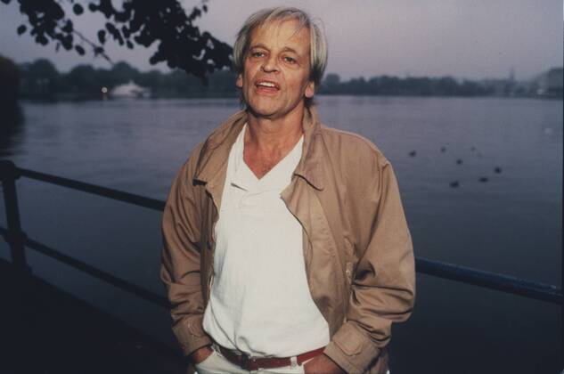 Klaus Kinski (Schauspieler) 10 85 vZ Mann TV Fernsehen Schauspiel Film Kino grauhaarig leger Jacke Hemd stehend draußen Wasser Fluß Geländer Ufer Park Baum halb quer neutral Farbnegativ Internegativ von Bild Nummer 372201