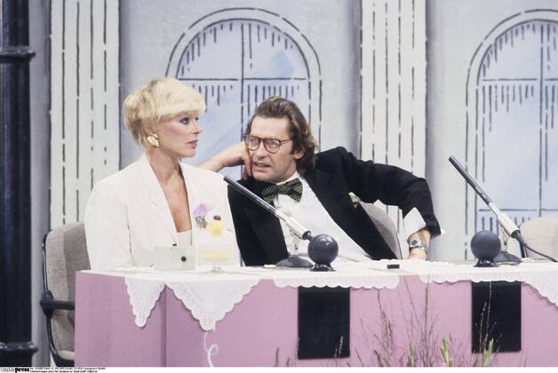 Helmut Berger und Elke Sommer in Dalli Dalli 09 85 ru Helmut Berger und Elke Sommer im September 1985 während einer Dalli Dalli -Sondersendung auf der IFA 1985 Internationale Funkausstellung Berlin TV Fernsehen Schauspiel Mann dunkelhaarig kurzhaarig halblang halblanges Haar Schauspieler Film seriös festlich Blazer Jackett Fliege Hemd Einstecktuch Brille Frau Schauspielerin blond kurzhaarig Blazer Applikation sitzend halb Kulisse Studio Fernsehstudio Fernsehshow Show Rateshow Spielshow Querformat quer halb stehend