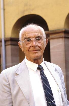 Prof. Dr. Bernhard Grzimek (Umweltschützer) 10 86 hör Mann TV Fernsehen Fotografie Tier Tierfilm Umweltschutz seriös Jackett Krawatte stehend draußen Brille Haus Gebäude Portrait hoch neutral