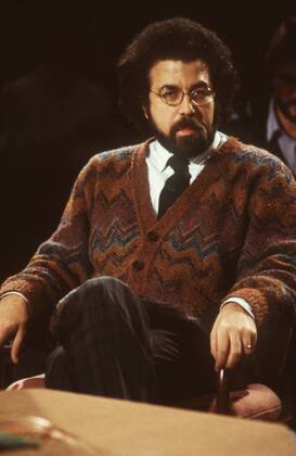 Giuseppe Sinopoli (Dirigent) 12 86 dar Mann Dirigent Musik klassische Klassik Oper dunkelhaarig kurzhaarig Locken Bart Schnäuzer Brille leger Strickjacke Jacke gemustert Hemd Krawatte sitzend Saal Studio dunkel halb hoch nachdenklich zuhörend festhaltend Lehne Stuhllehne