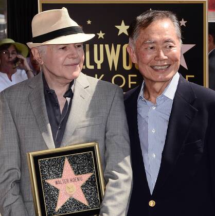 Actor Walter Koenig (L) holds a replica plaque as he poses with actor George Takei during an unveiling ceremony honoring him with the 2,479th star on the Hollywood Walk of Fame in Los Angeles on September 10, 2012. Koenig is the final member of the Star Trek television show to receive a star. Looking on rear is actor Leonard Nimoy.  LAP2012091024