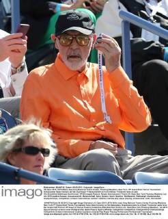 US Open 2013, USTA Billie Jean King National Tennis Center, Flushing Meadows, New York, ITF Grand Slam Tennis Tournament . Schauspieler Sean Connery auf der Zuschauer Tribüne,klemmt sich ein kleines Transistorradio an sein Ohr,Einzelbild,Halbkörper,Hochformat, VIP,Ehrengast,Feature,