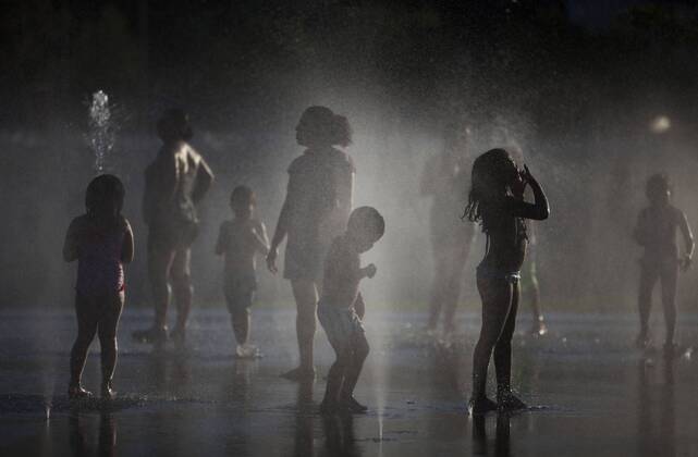 People enjoy in a font on the Manzanares riverside. After of a rare cold weather finally arrived the heat to Madrid city. Spain.