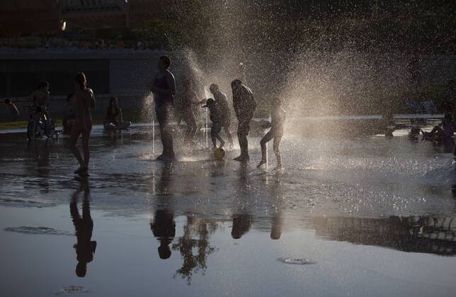 People enjoy in a font on the Manzanares riverside. After of a rare cold weather finally arrived the heat to Madrid city. Spain.