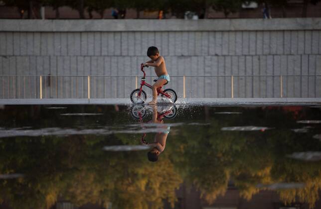 People enjoy in a font on the Manzanares riverside. After of a rare cold weather finally arrived the heat to Madrid city. Spain.