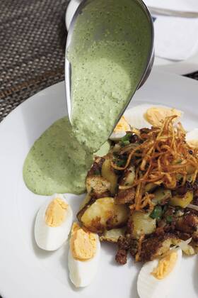 Close up of hard boiled eggs with roasted potatoes, onions and pouring Frankfurter Sauce  CSF015125