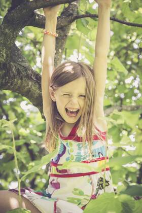 Portrait of laughing little girl climbing on a tree in the garden model released Symbolfoto  SARF000784
