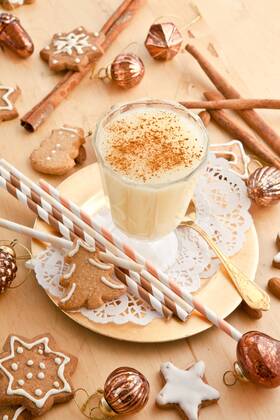 Ein Glas Eierpunsch mit Zimt und Weihnachtsdekoration  1079701655